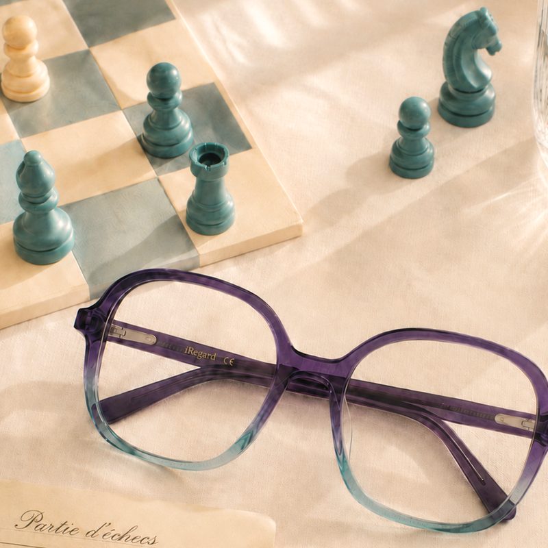 Monture Droit de Regard en acétate dégradé violet et bleu près d'un échiquier